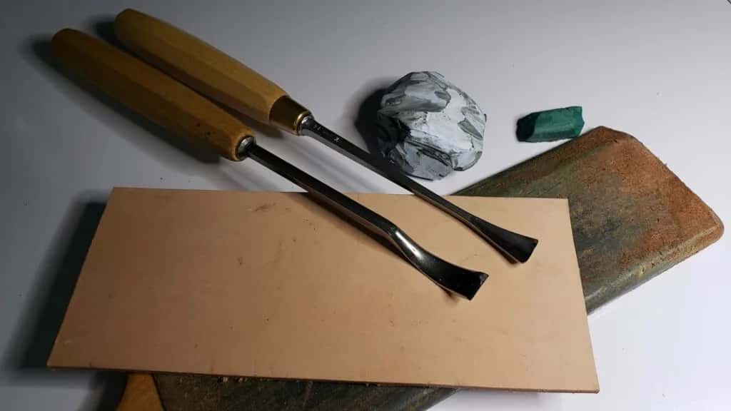 Two gouges beside a sharpening stone and a leather strop, which is the whole kit for the first month