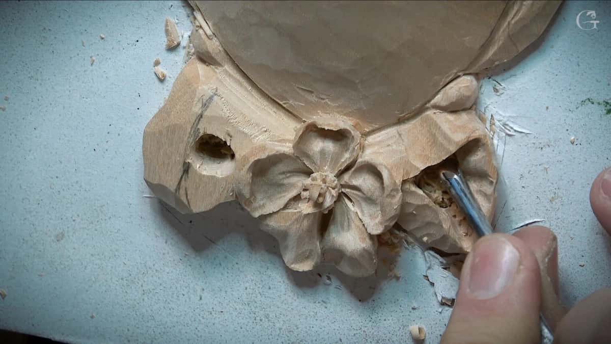 Close view of a gouge undercutting the petals of a carved flower rosette