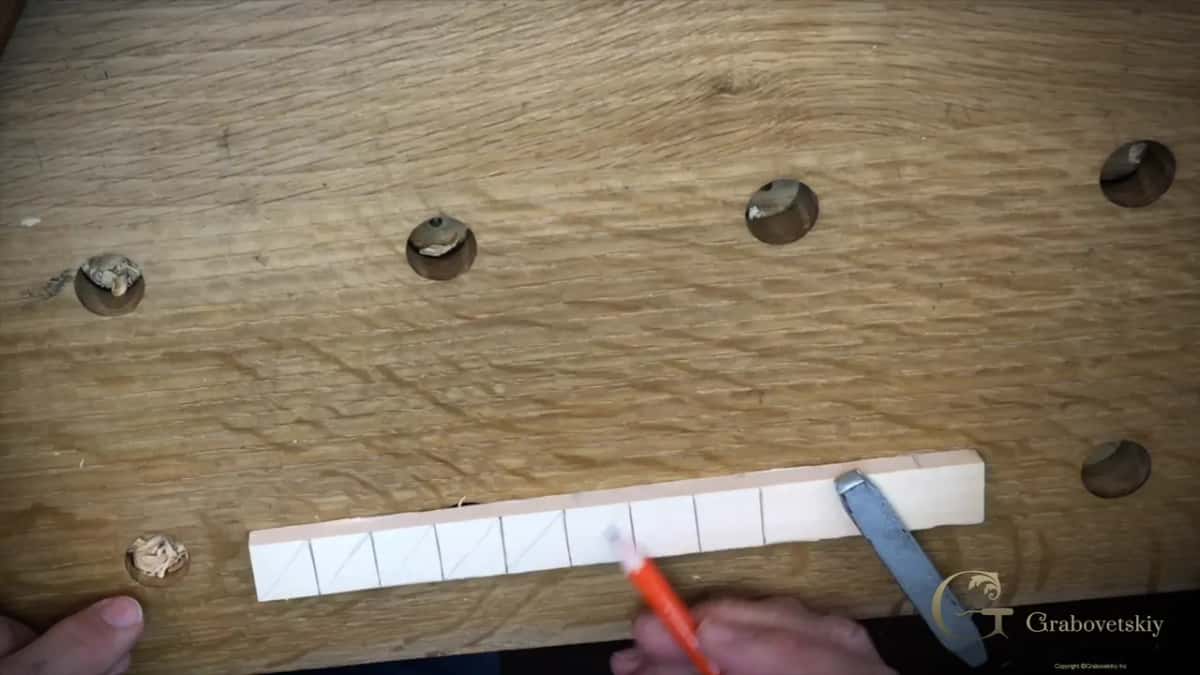 Pencil diagonals drawn inside every space of a basswood molding strip before any cutting starts