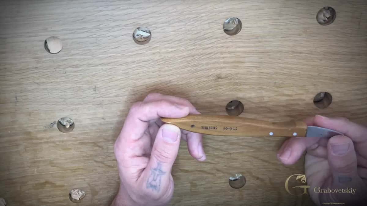 Chip carving knife by Pfeil held in the hand with the Swiss maker stamp showing on the blade