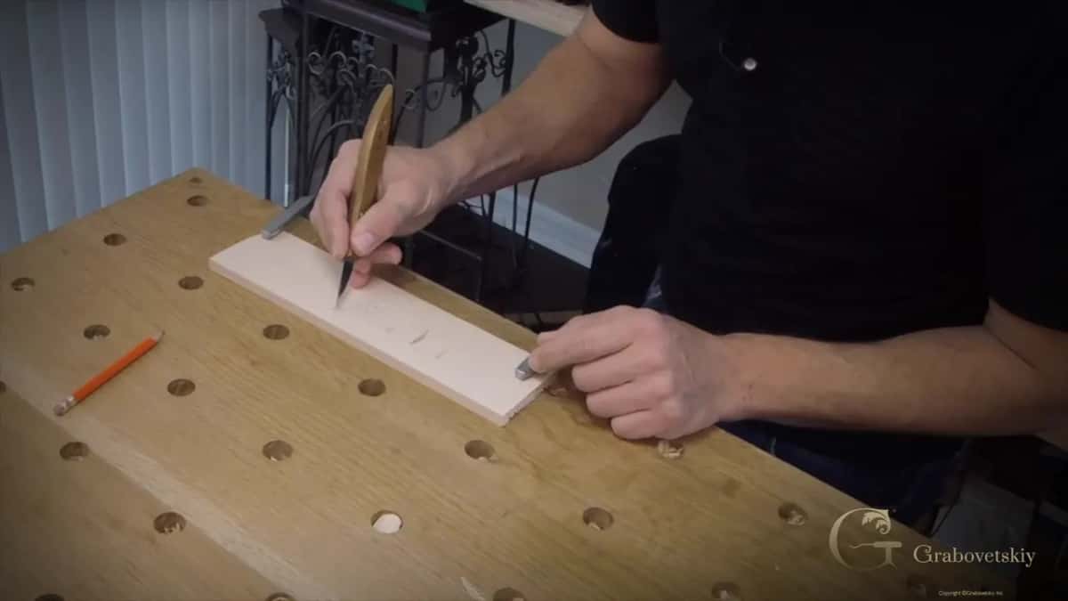 Holding a carving knife in the pencil grip while cutting a small leaf and stem design in basswood