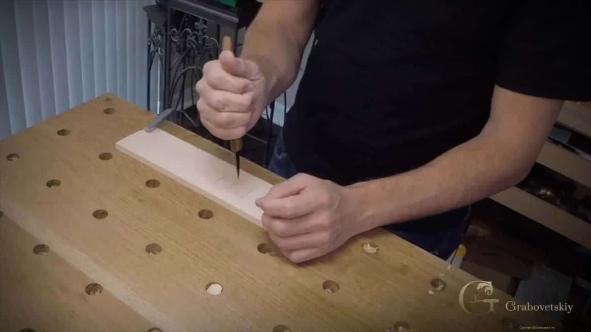 Knife driven straight down at ninety degrees into a clamped basswood board to make the first stop cut
