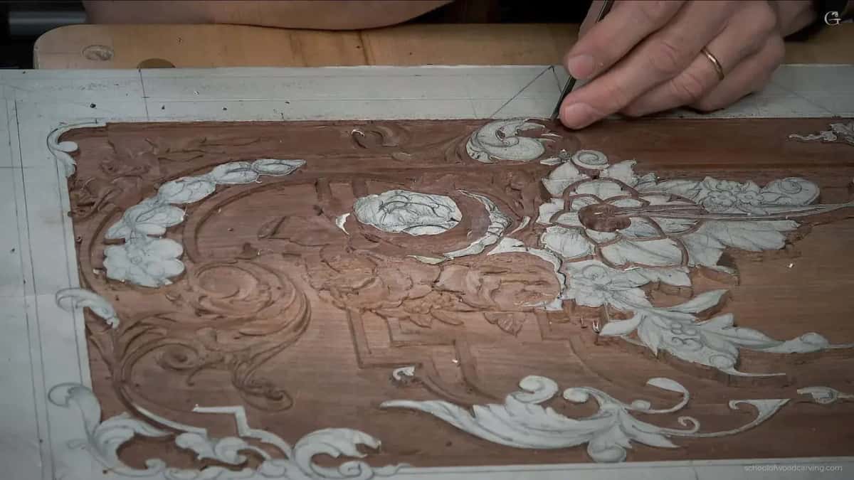 A hand carving into a hardwood furniture panel where the ornament is drawn in white and half of it is already cut away