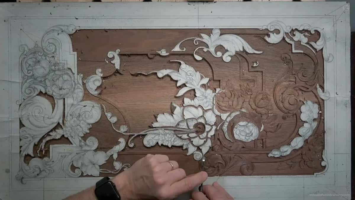 A walnut furniture panel seen from above, half of the ornament still in pencil and half of it carved away