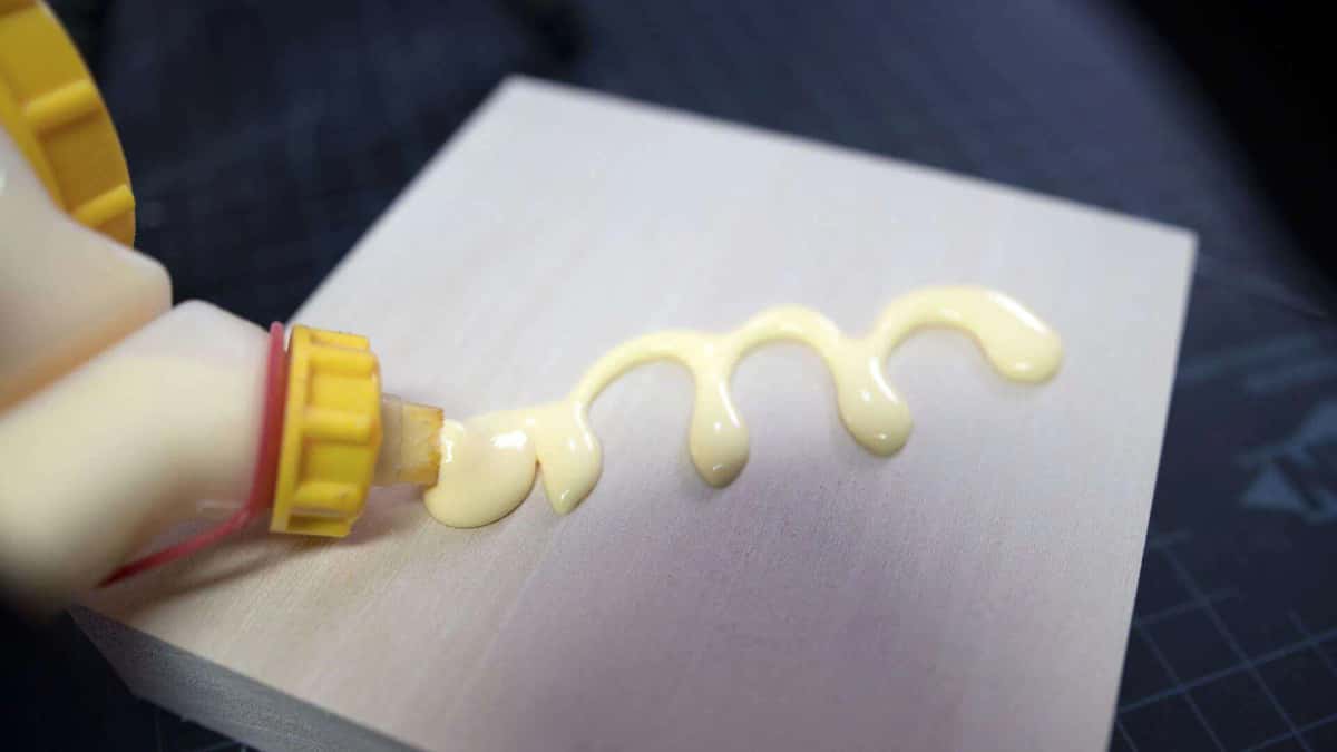 Yellow wood glue laid down in a bead across a basswood rosette blank