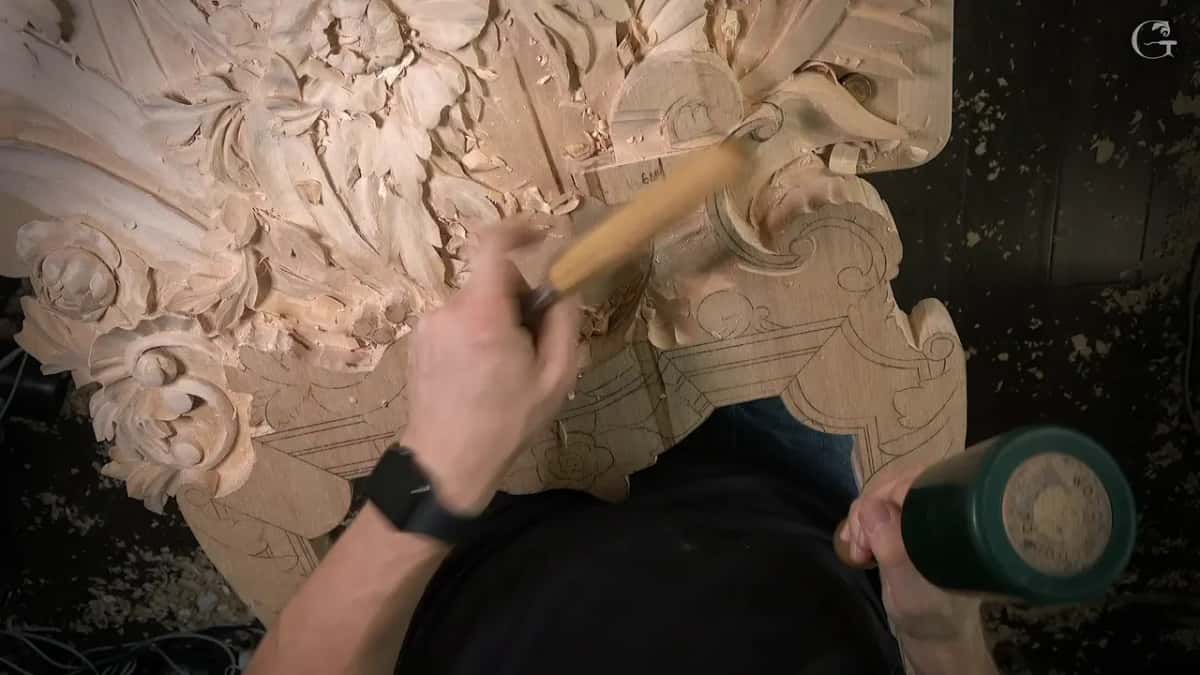 From above, the green mallet and a chisel work over the half carved panel, rosettes at the left