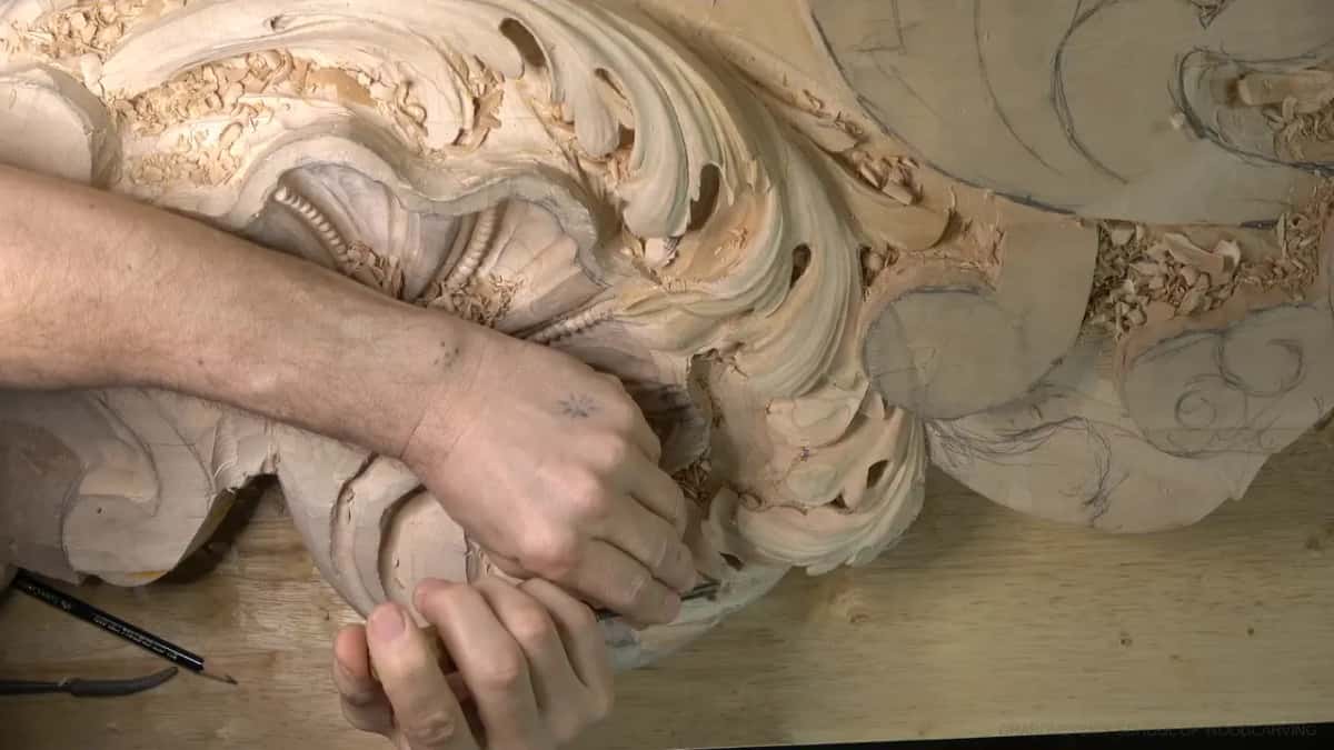 A small knife and pencil lie by the panel as both hands work the right side.