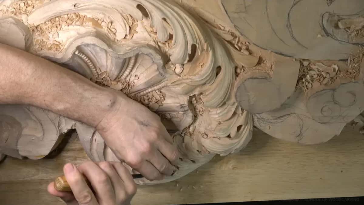 Two hands work the lobe's right side, chips everywhere.