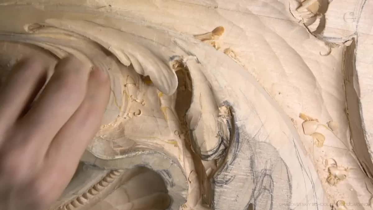 Hand flat on the leaf, cutting near the curl.