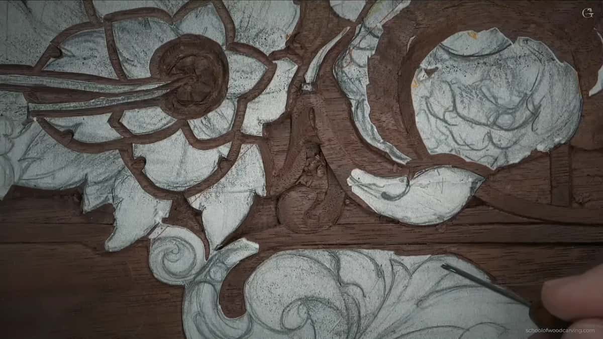 Carved scroll fills the frame with a hand entering at the lower right.