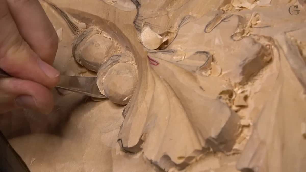 Close in, a gouge slides along the side of the two acorns where they meet the curved wall