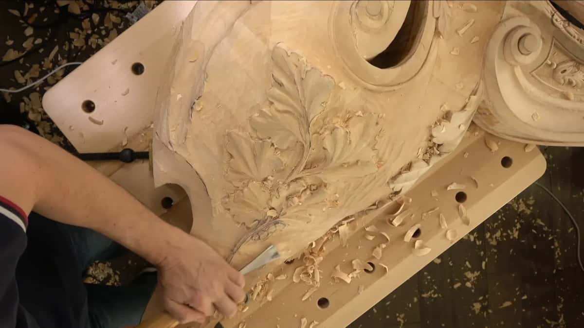 From high above, the whole piece on its bench, a big scroll at top right and an arm working by the stem