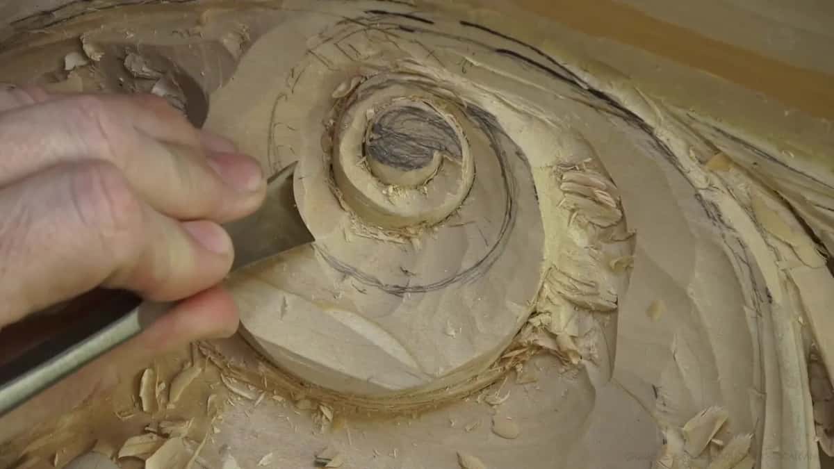 Hand and gouge working into the eye of a volute, shavings packed round the barrel