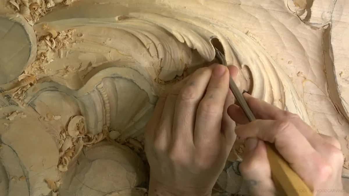 Two hands guide a bent gouge through the hollow.
