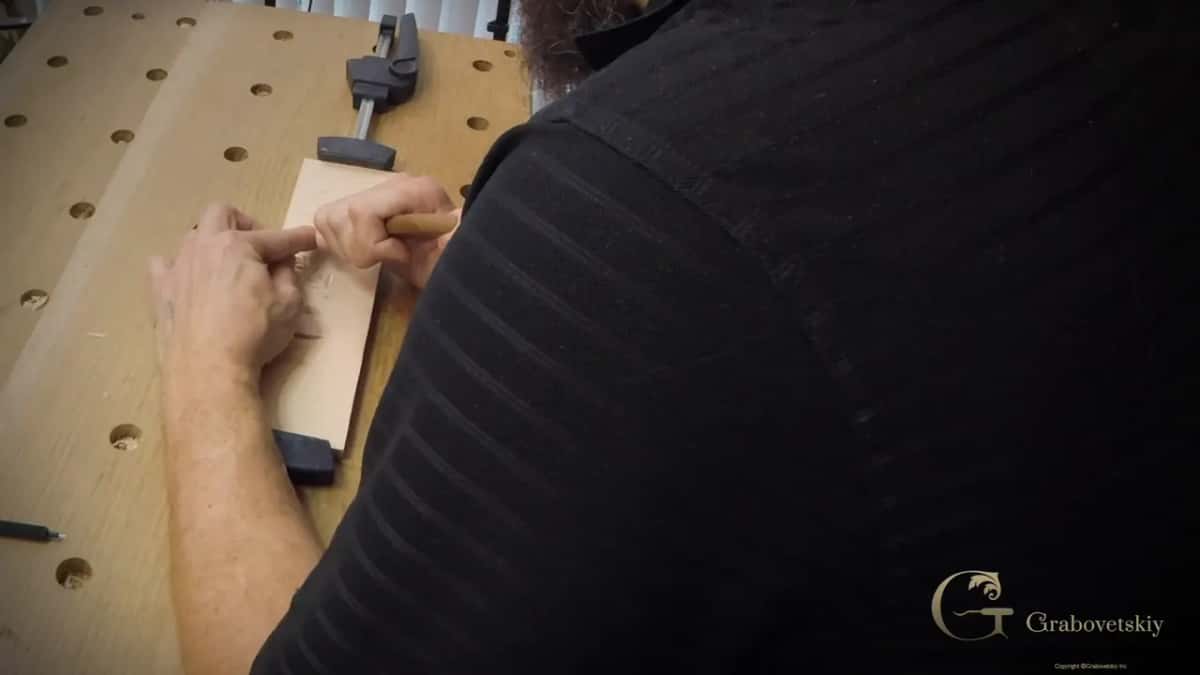 Two hands on the small board, close in, one pressing it flat while the other works