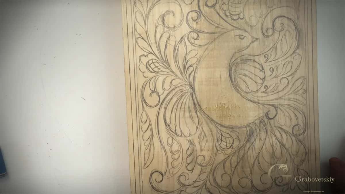 Finished drawing on basswood, a stylized bird wrapped in curls and small flowers.