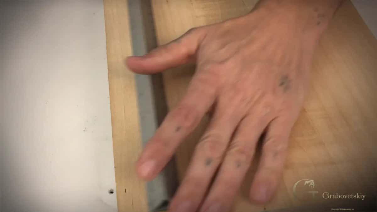 Steel scale held flat while the pencil rides along its edge.