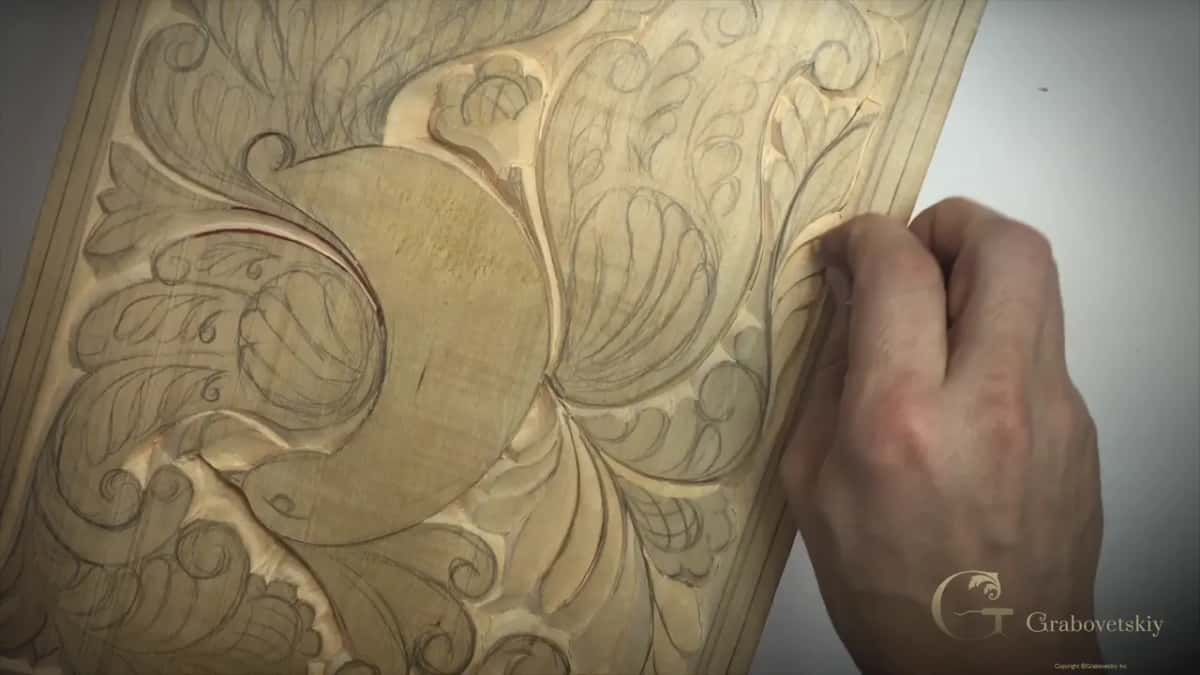 A scrap of wood held against the board, the way carvers smoothed grain before abrasives existed.