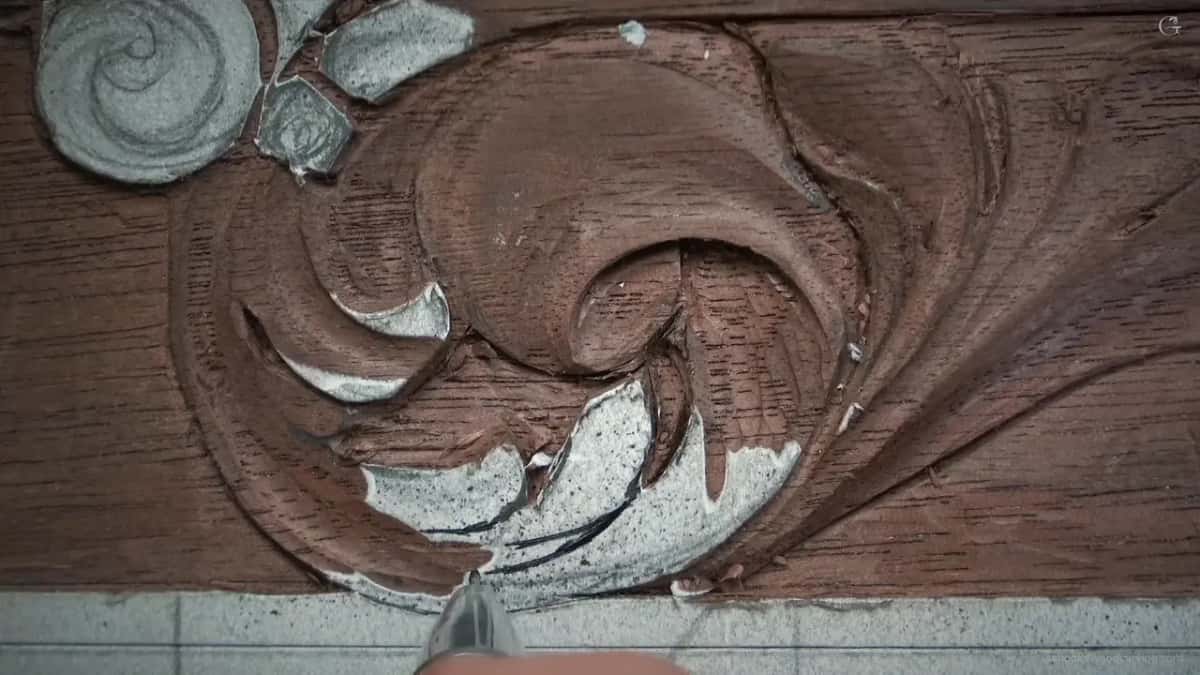 Carved scroll with a tool resting at the bottom edge and two separations visible.