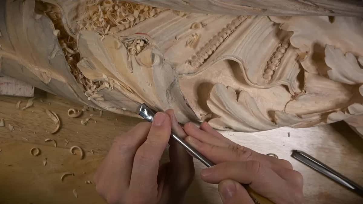 Both hands drive a tool along a leaf edge below a spiral