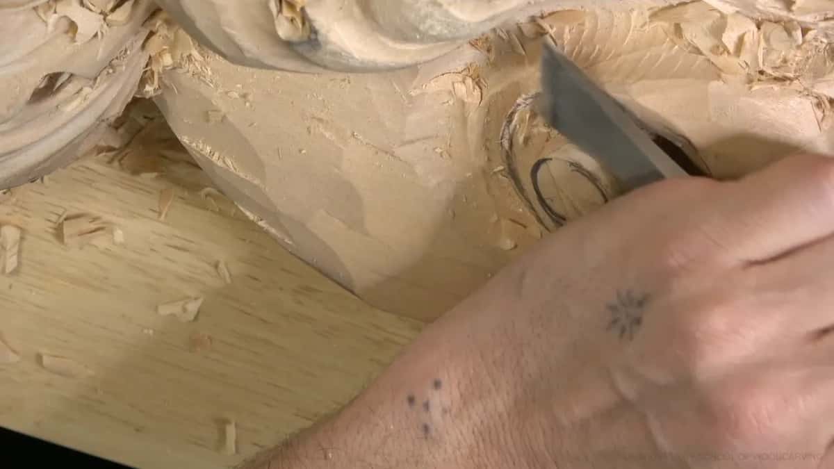 A hand lays a broad blade flat across the rolled surface.
