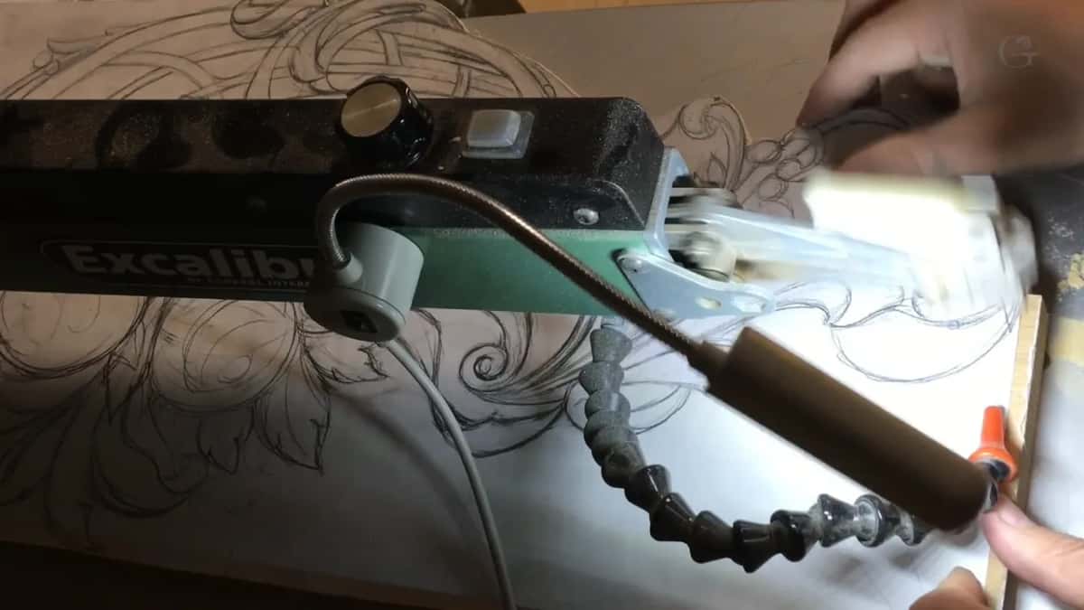 Scroll saw with the design drawn straight onto the board, blade coming down on the line