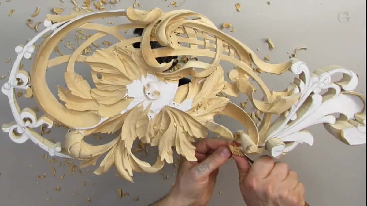Bare hands low on the panel, working a curl next to the white scroll