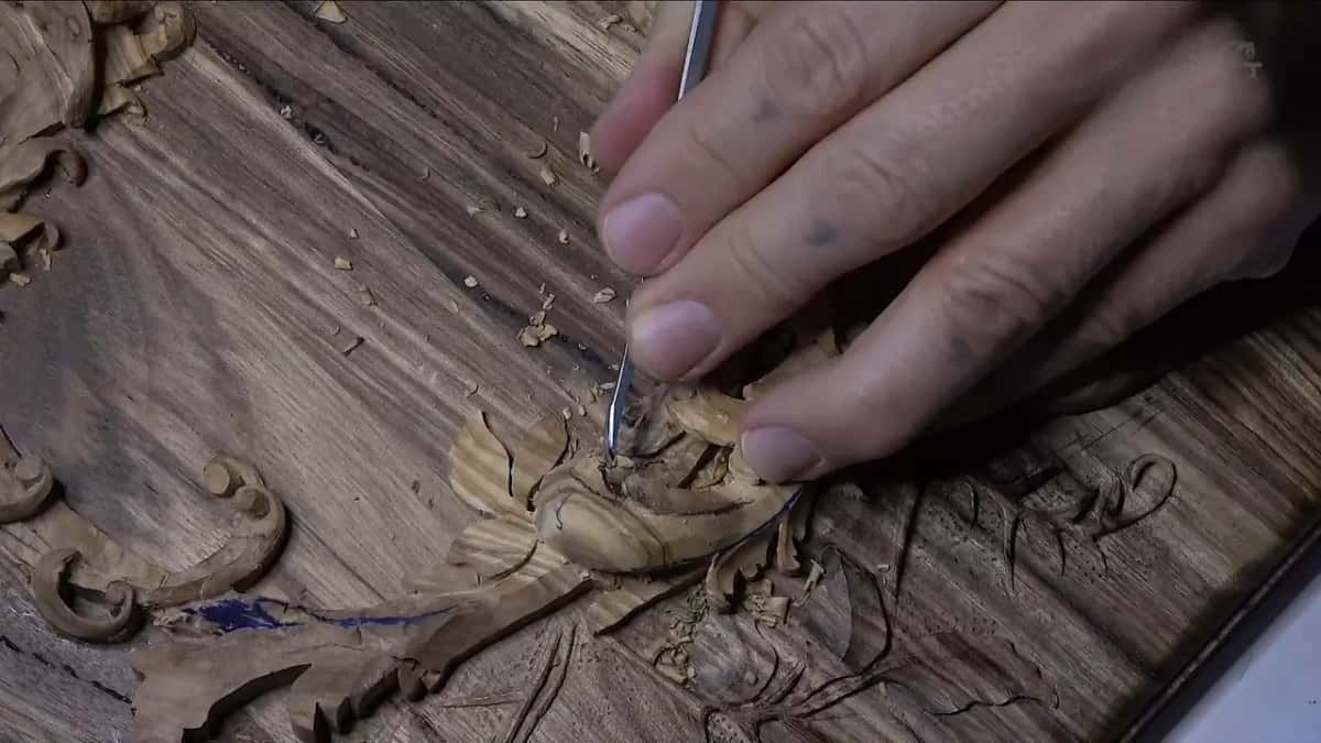 Three fingers guide a narrow gouge into the heart of the curl