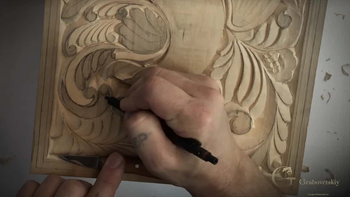 Pencil in one hand, the knife lying flat on the board beneath it.