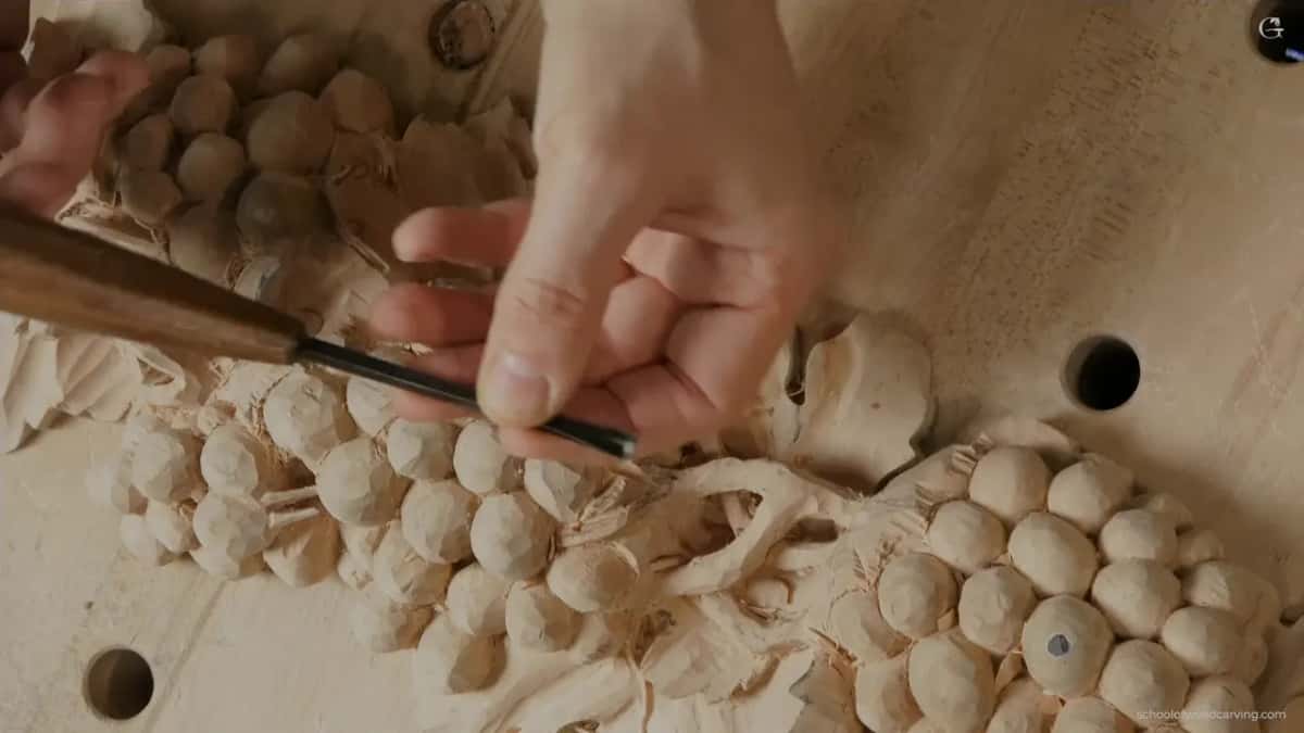 Both hands on the gouge, working in the middle of the fruit where the stem will pass through
