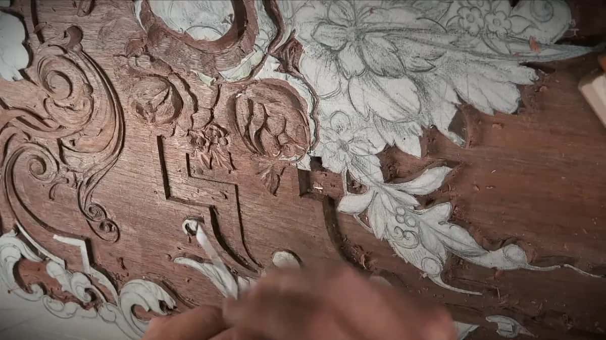 Blurred fingers at the bottom, the carved roses and their leaves above them