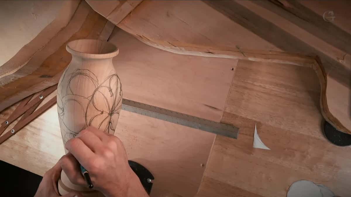 Boundary circles drawn straight onto the bare vase in pencil, with the calipers lying on the bench beside it