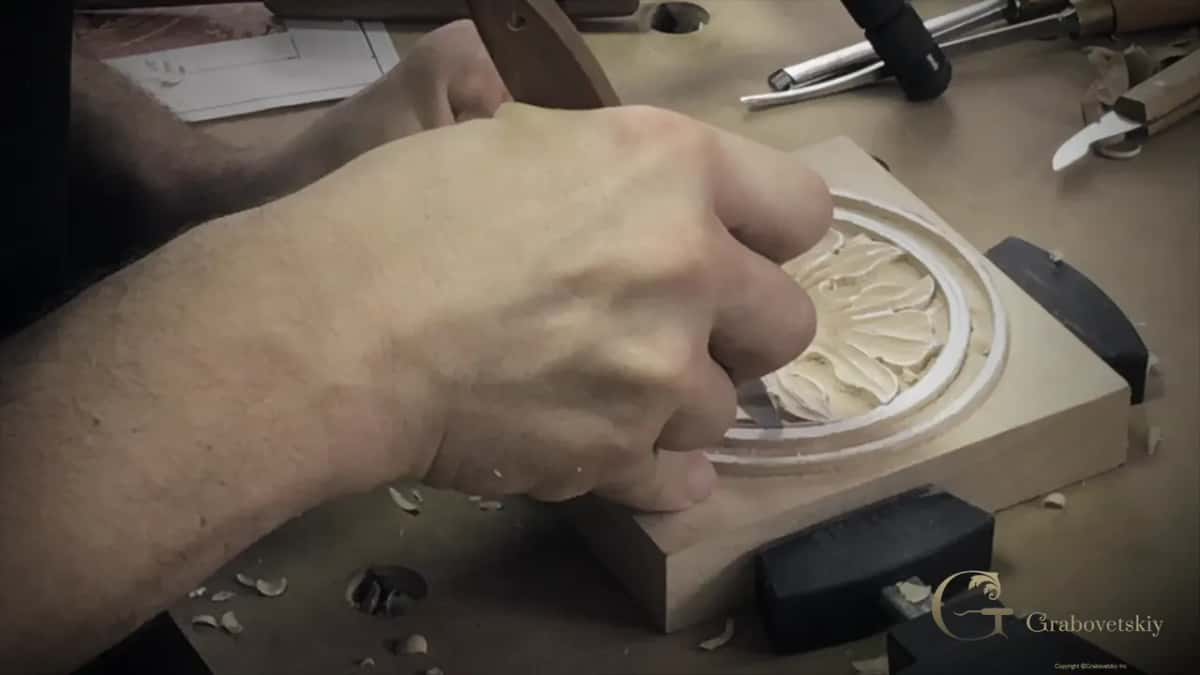 Steel punches laid out beside the finished carving, waiting for the background stage