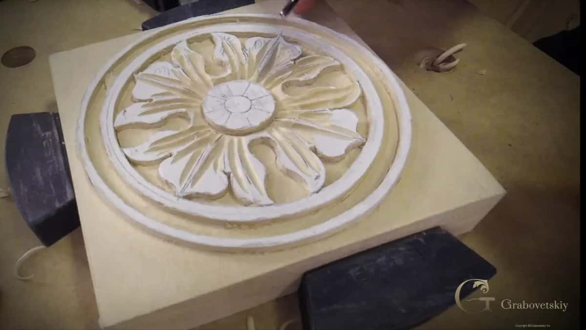 The flower fully formed, both hands holding the block steady while the last cuts go in