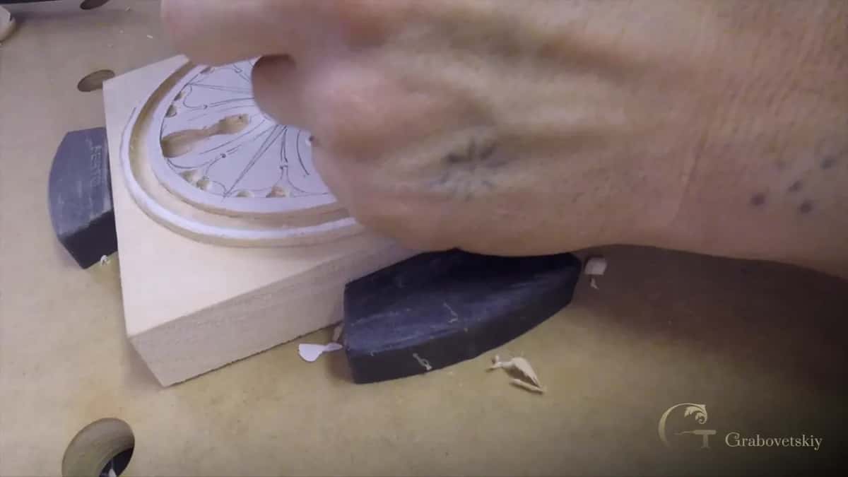 A hand comes across the carved face, the ground already cut away all round the ring itself