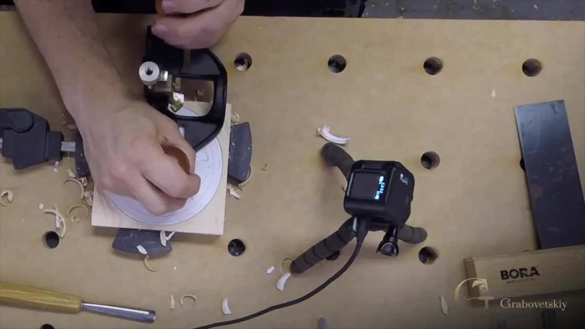 Both hands on the router plane, sweeping it across the ground at a set depth
