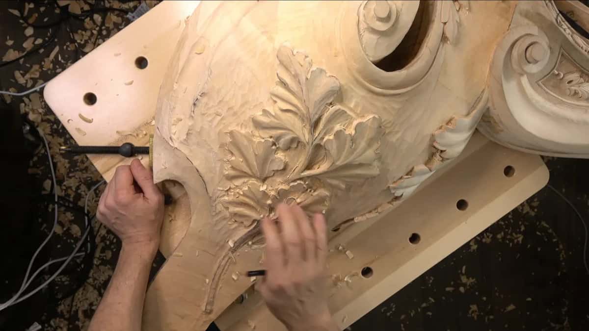 One hand turning a bench clamp screw at the corbel edge