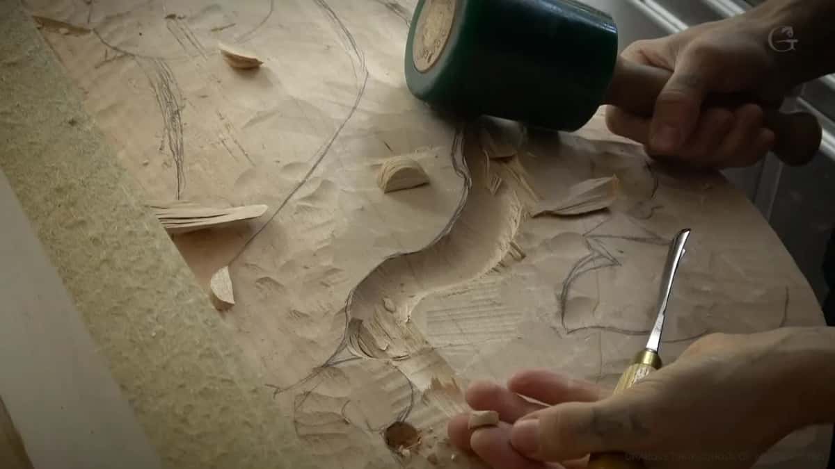 Mallet held high over a small gouge, loose chips in the corner.