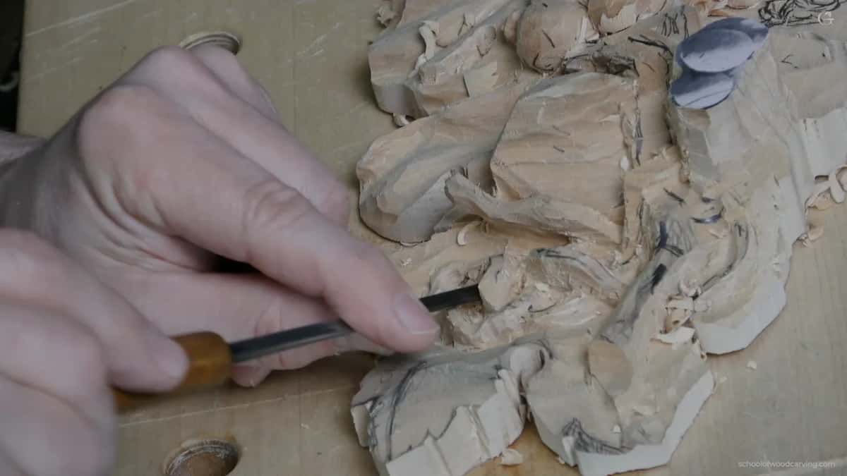 Both hands bring a gouge in flat, and the same junction gets worked from the opposite direction next