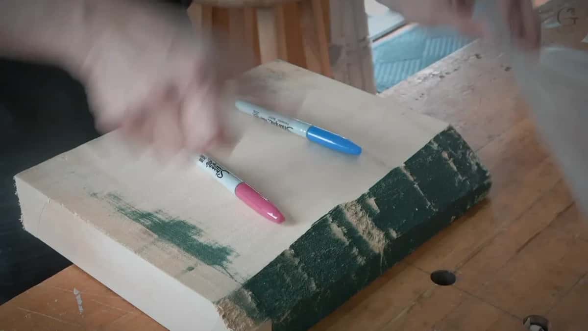 Blue and red Sharpie markers lying on a two inch basswood blank, hands moving above them