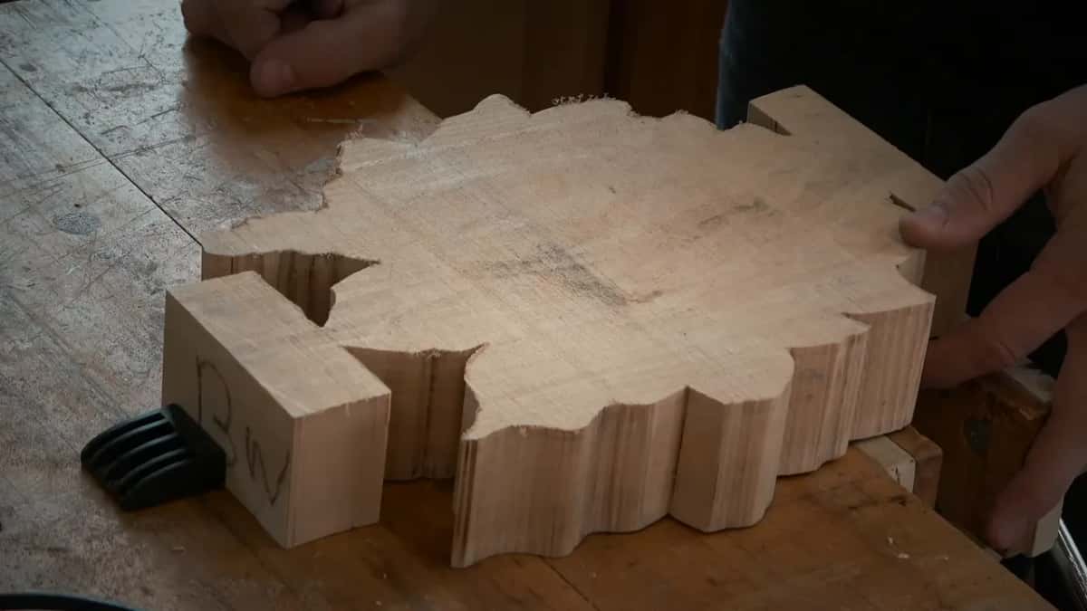 Blank set face down on the bench showing its flat sawn back, hands steadying it by the square tabs at either end