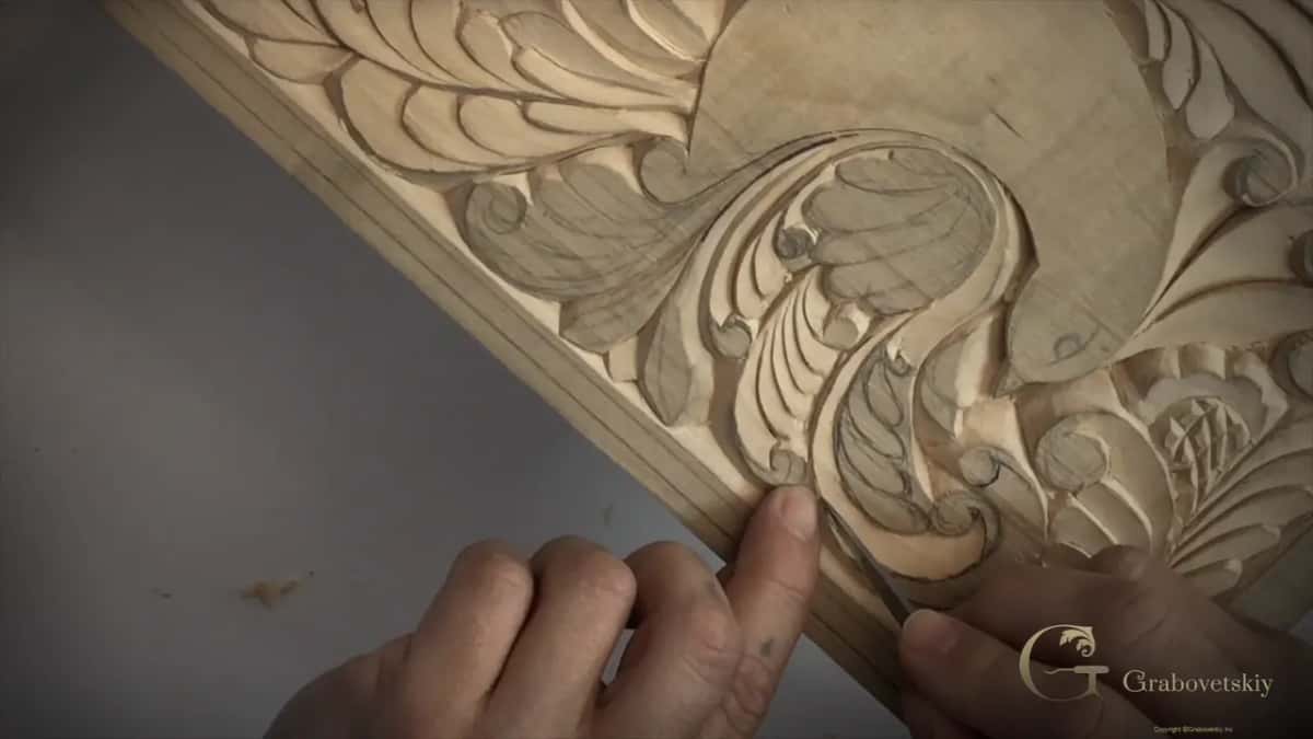 Both hands over the panel where the wall between line and edge has gone thin, so the weight comes off the blade.