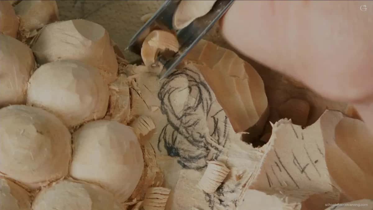 Pale handled gouge going into the pencil work, stopping short of the line