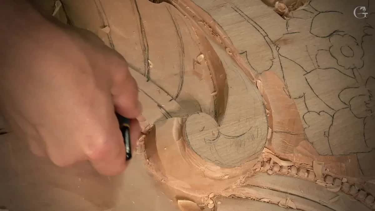 Marker in his hand over a shaped volute, a finished row of beads running along the lower right edge