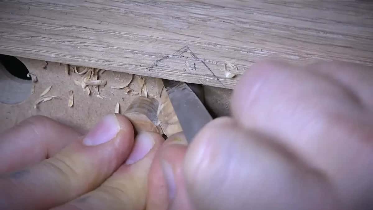 Knife blade working an olive hard against the edge of the oak