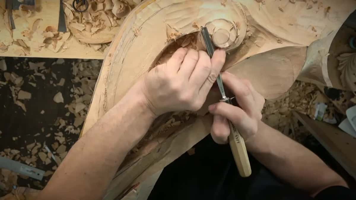 Straight down Both hands driving a Swiss Made gouge straight down beside a carved boss