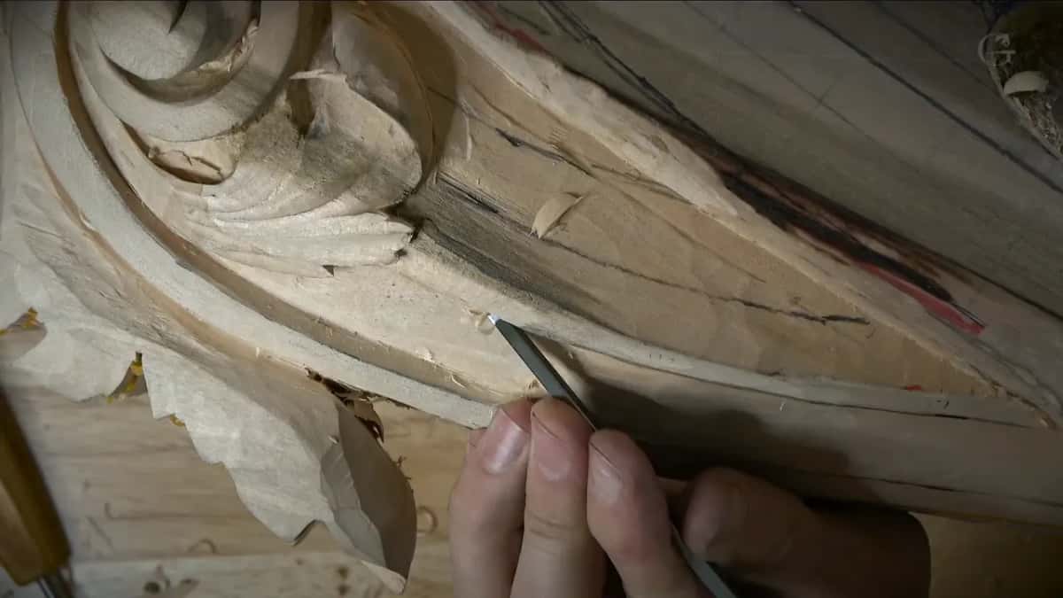 Both of them Fingers steadying a small dark tool right where the scroll runs out into the plain edge