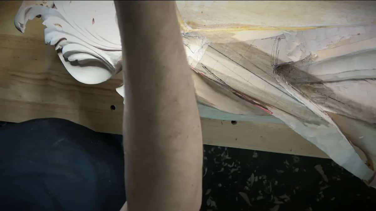 Across the frame Forearm filling the frame, the corbel edge and its taped paper behind