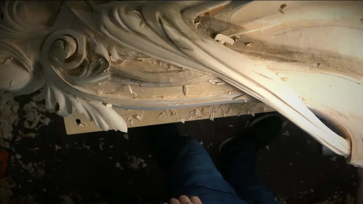 Step away Looking straight down past his own legs at the carved corbel