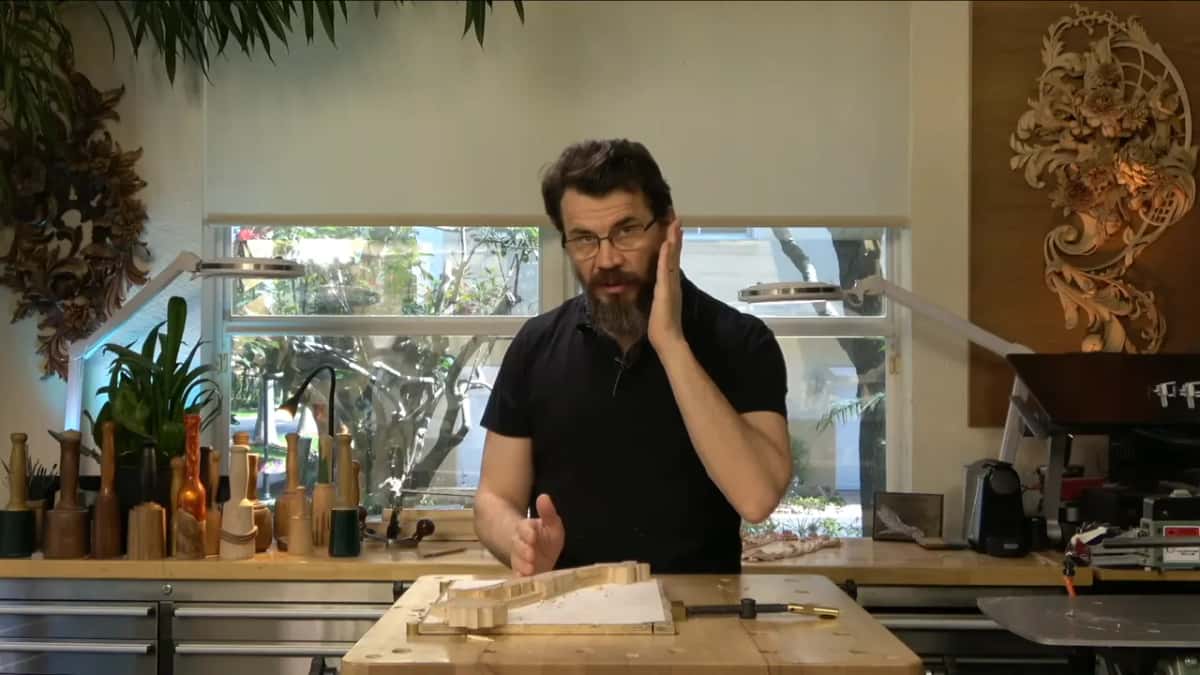 In his studio at the bench, one hand on his cheek
